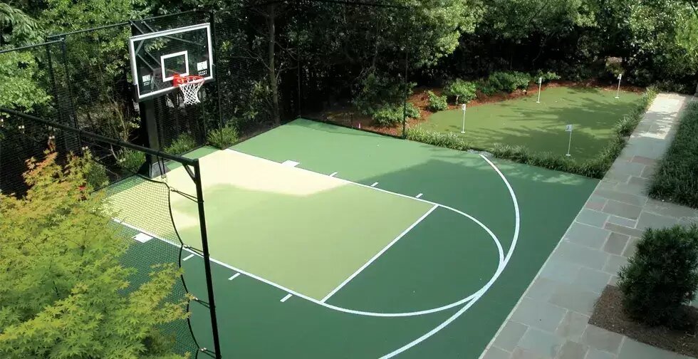 Green multi-sport court set into a landscaped backyard