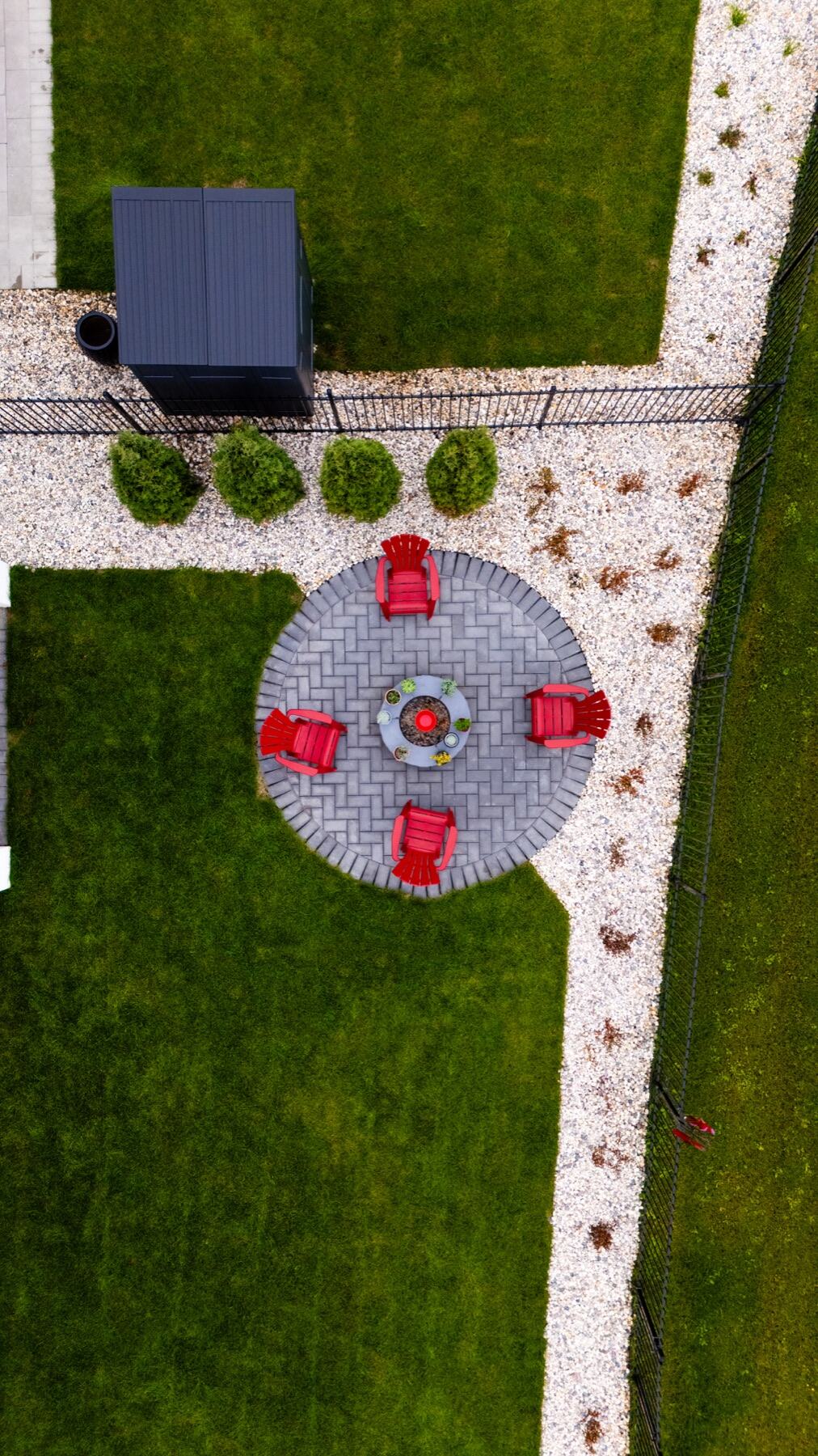 Aerial view of a circular paver fire pit with red chairs