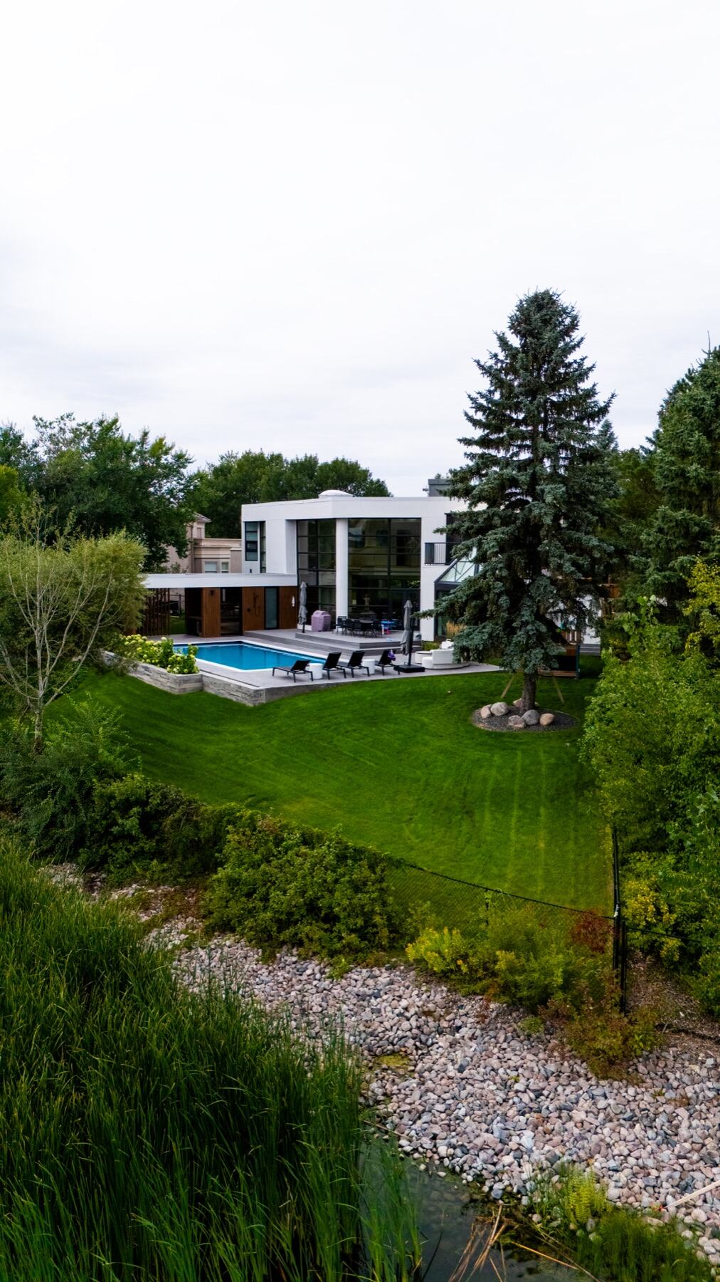 Aerial view of a modern lakeside home with pool and lawn