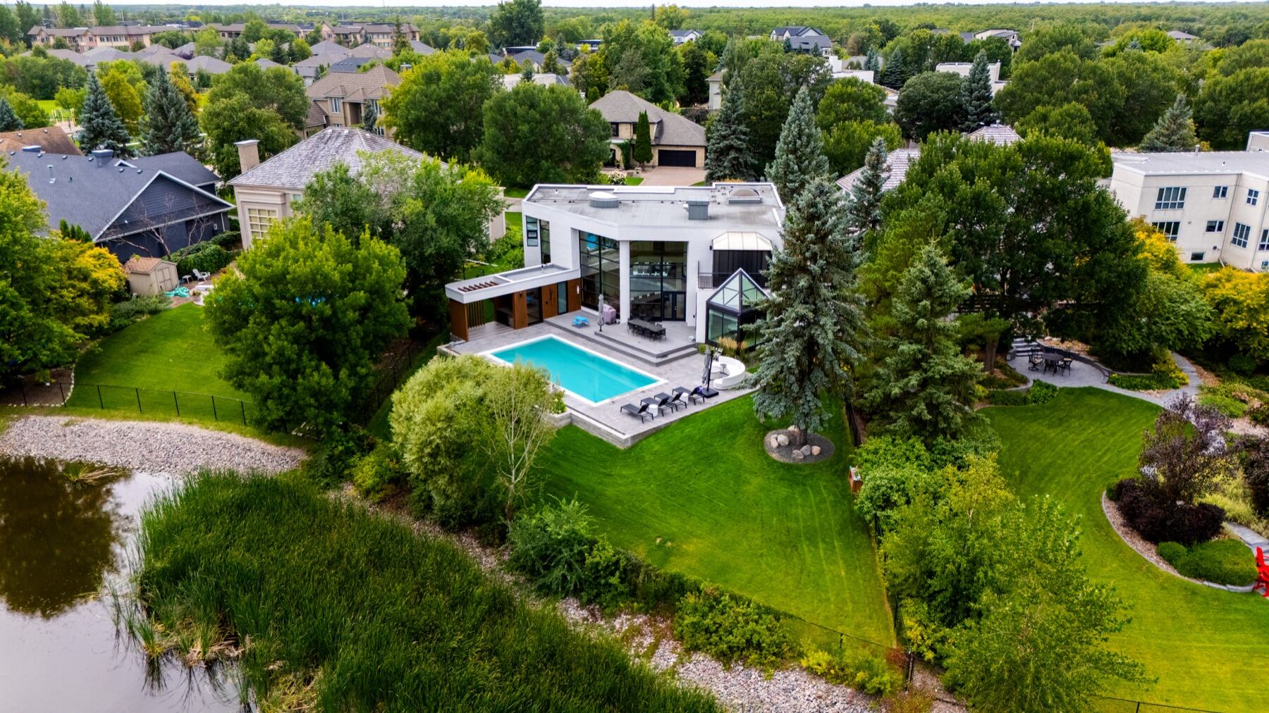 Aerial view of a modern home with pool, patio, and mature trees
