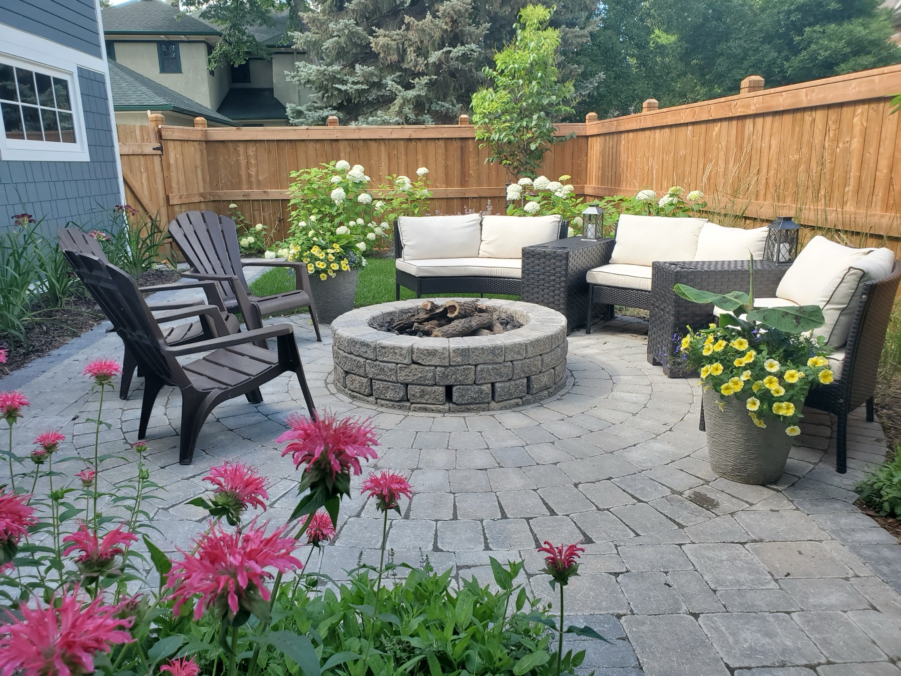Paver fire pit circle with lounge seating and perennial beds