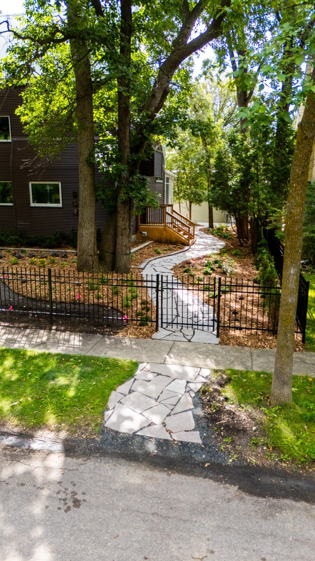 Flagstone path leading to an iron gate under mature trees