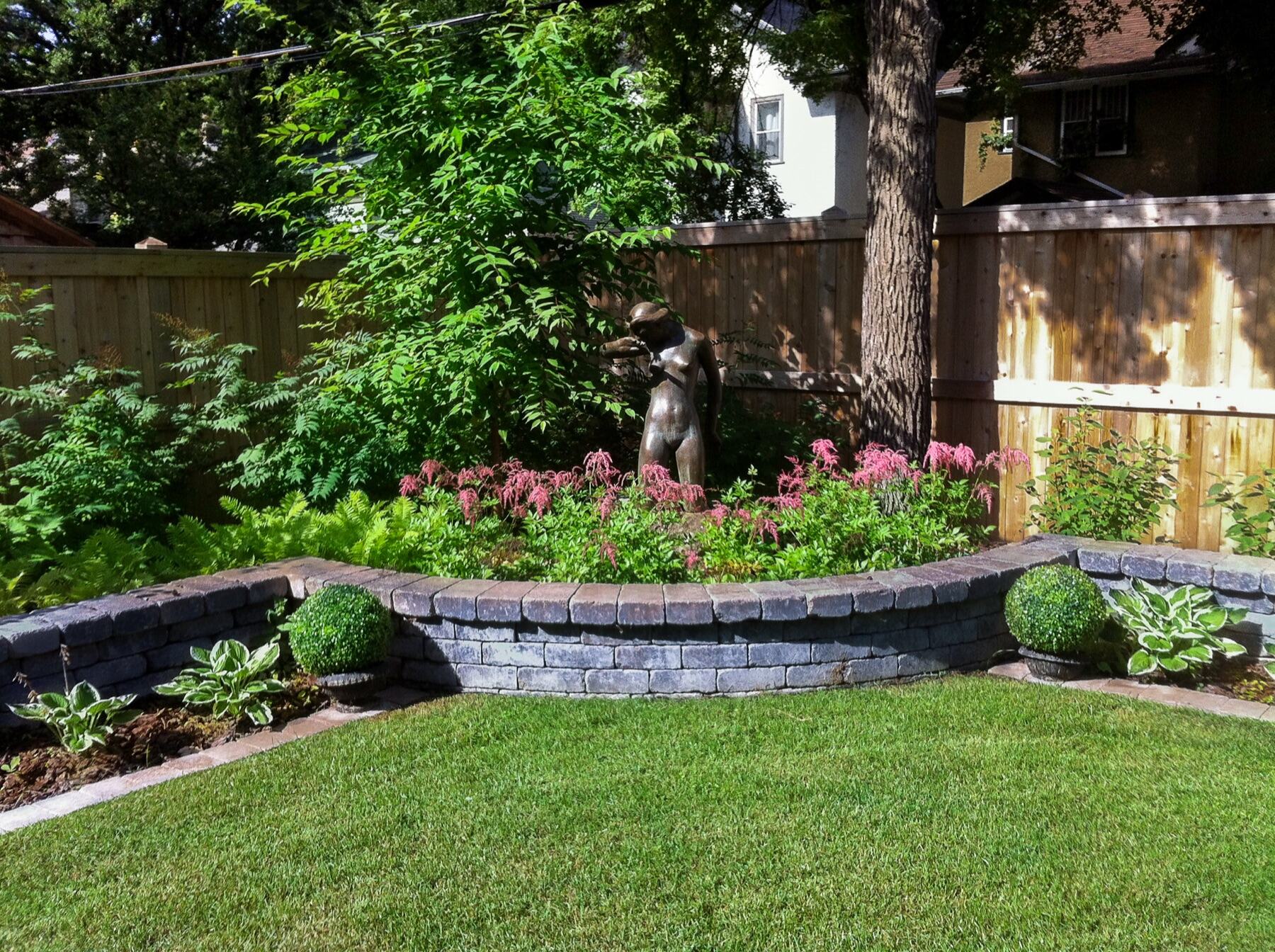 Stone retention wall and cedar fence around a garden bed